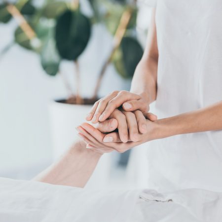cropped shot of reiki healer holding hand of male hand